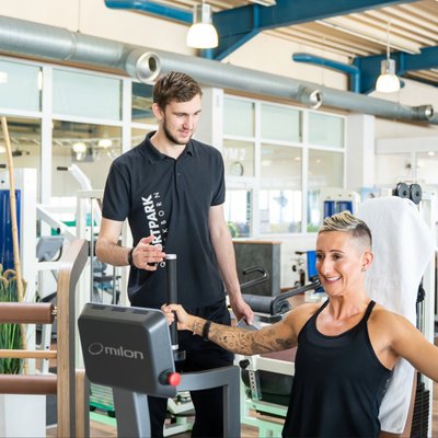 Sportpark Quickborn: Training einer Frau am Fitnessgerät, betreut durch einen Fitness Trainier.