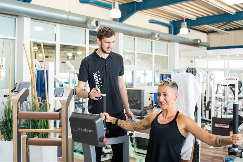 Sportpark Quickborn: Training einer Frau am Fitnessgerät, betreut durch einen Fitness Trainier.